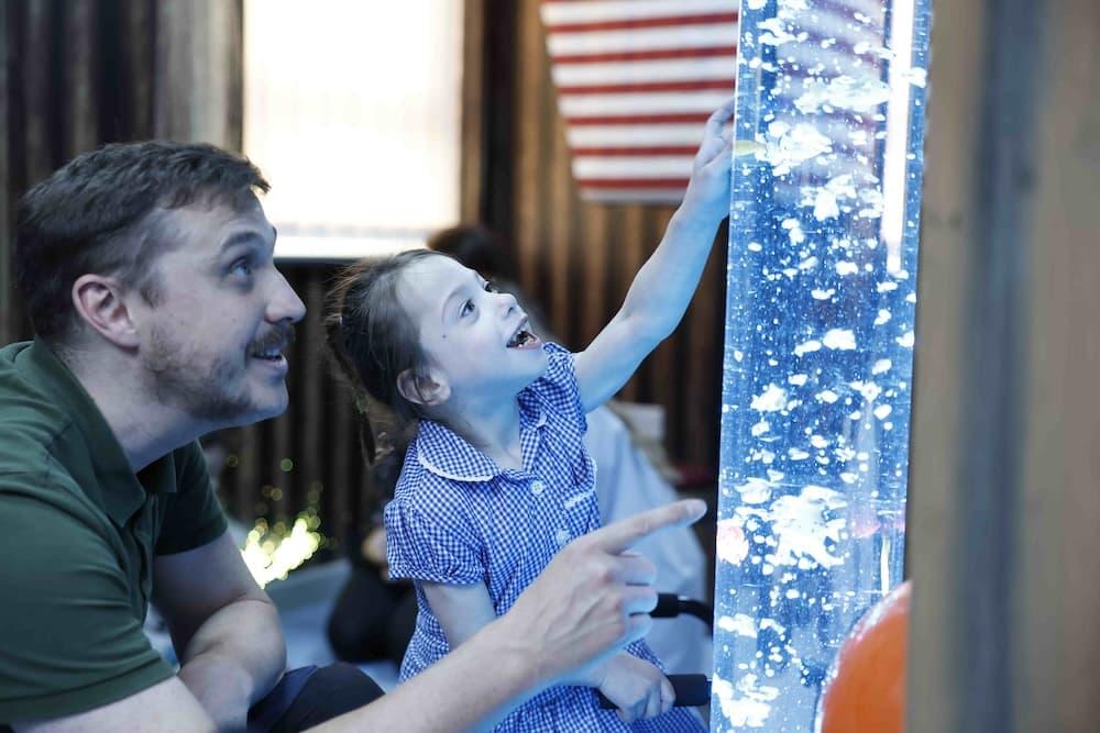 A man and a little girl are pointing towards an interactive sea life-inspired environment. They are both smiling in awe.