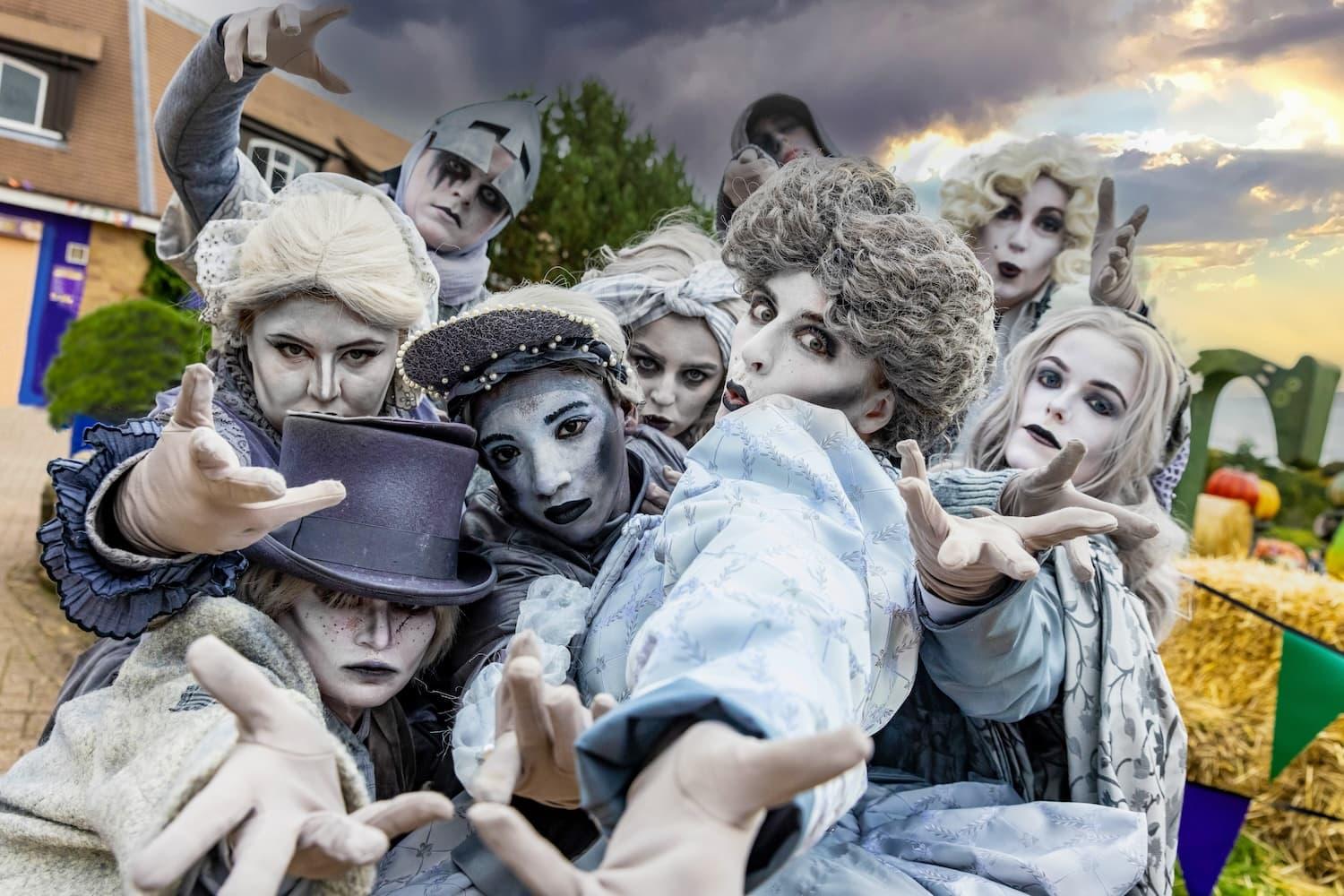 Several actors are dressed in silver outfits wearing silver face paint and hair spray.