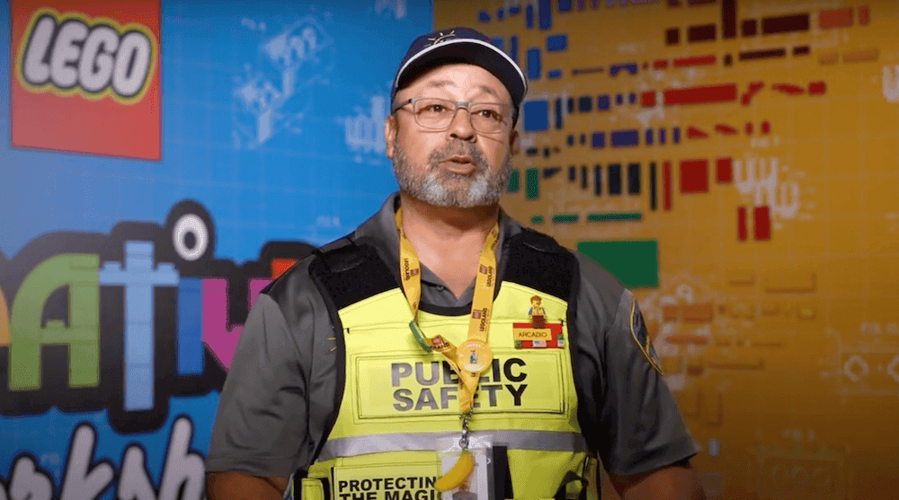 Man in a high-visibility jacket and black cap standing infront of a LEGOLAND® background.