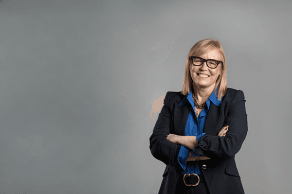 Merlin's CEO, Fiona Eastwood, pictured against a lit grey background. Her arms are crossed and she is smiling.